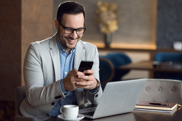 Mid adult happy businessman reading a text message on mobile phone