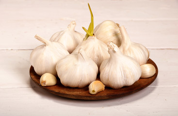 Garlic Cloves and Bulb in vintage wooden plate on white wooden table.