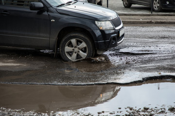 The car goes without reducing speed on a bad road with asphalt in pits and potholes, hitting the...