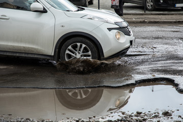 The car goes without reducing speed on a bad road with asphalt in pits and potholes, hitting the...