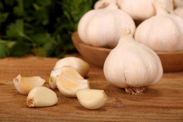 Garlic Cloves and Bulb in vintage wooden plate on wooden table.
