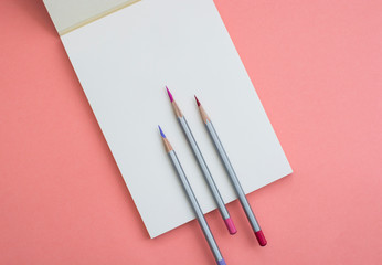 Notebook with a pencil on a pink background.