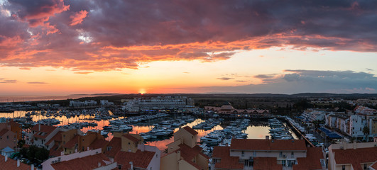 Fototapeta na wymiar Aerial panoramic view of the Vilamoura marina in Portugal as the sunsets in the distance on a dramatic cloudy day.