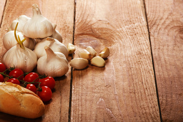 Tasty bread with garlic, Small red cherry tomatoes on kitchen wooden table. Place for text, copy space