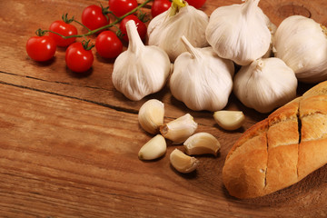 Tasty bread with garlic, Small red cherry tomatoes on kitchen wooden table. Place for text, copy space