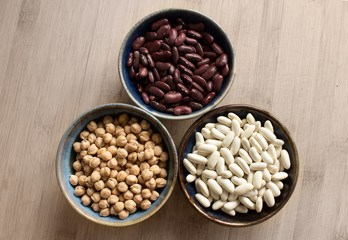 Chickpeas, red beans and white beans in ceramic bowls. Top view.