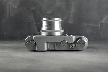 Old rangefinder film camera on grey cement background.