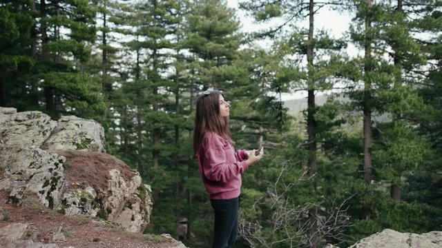 Teenage girl taking photos in a pine forest