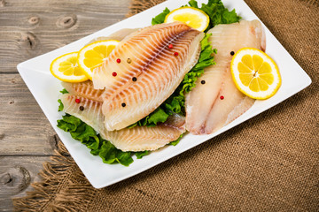 Whitefish Tilapia Fish Raw Fillet on Wooden Background. Selective focus.