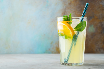 glass with lemonade or mojito cocktail with lemon and mint, cold refreshing drink or beverage with...