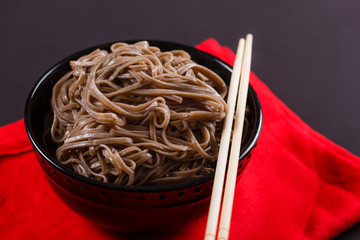 Buckwheat noodle in a black bowl on a dark background