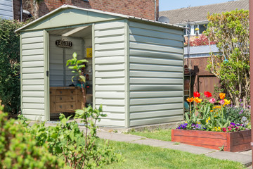 A modern shed and breautiful grden with blooming flowers and a Dads hideout sign in the shed.