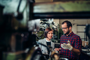 Machinist discussing with female supervisor at factory