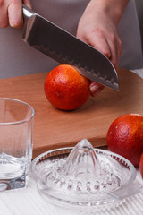 young woman in a gray apron cuts blood orange