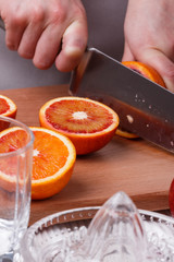 young woman in a gray apron cuts blood orange