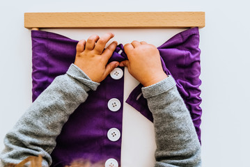 Hand of a student handling montessori material inside a classroom.