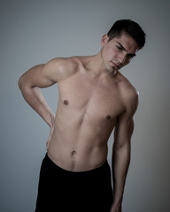 Fototapeta premium Silny młody człowiek cierpiący na bóle krzyża w stresie i złej postawie