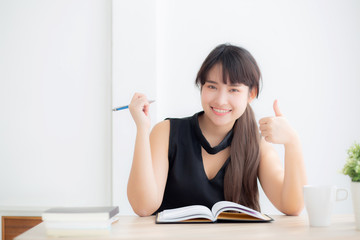 Fototapeta na wymiar Beautiful portrait young asian woman smiling sitting study and learning writing notebook and diary in the living room at home, girl homework, business woman working on table, education concept.