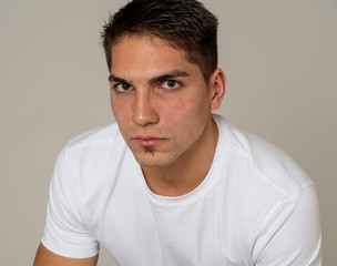 Fototapeta premium Natural portrait of young attractive man in his 20s looking and posing with neutral face expression