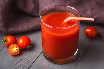 Tomato juice in glasses on gray wooden table.