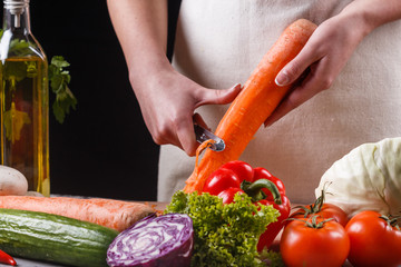young woman in gray apron peeling carrots