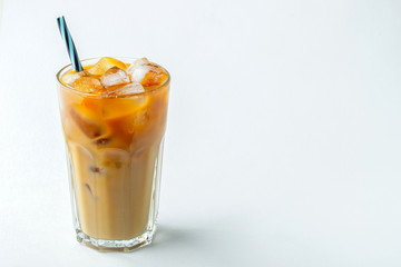 Ice coffee in a tall glass with cream poured over and coffee beans. Cold summer drink on a light background. With copy space