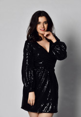 Fototapeta premium Young beautiful brunette woman in black modern spring jacket dress posing on gray 