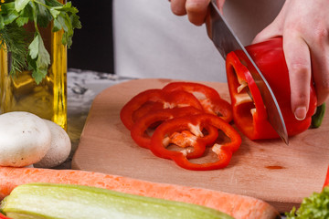 young woman slicing peppers in a gray apron