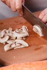 young woman slicing mushrooms in a gray apron