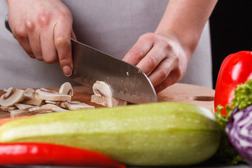 young woman slicing mushrooms in a gray apron