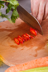 young woman slicing peppers in a gray apron