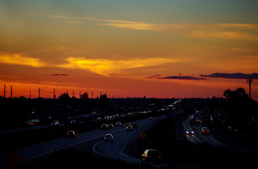 Sunset over city cars on highway road on sunset evening night in urban view