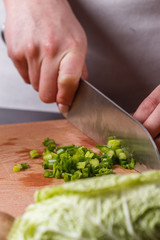 young woman slicing herbs in a gray apron