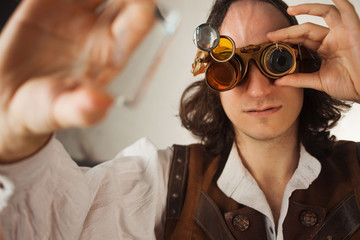Steampunk style researcher mechanist of the monocle with a large number of lenses looking at...