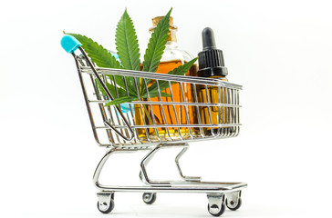 Supermarket trolley with marijuana leafs and medical cannabis oil cbd, isolated on white
