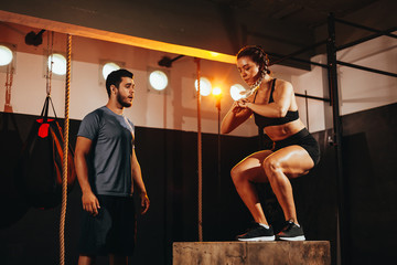 Fototapeta na wymiar Fit young woman doing a box jump exercise. Sports woman doing a box squat at the gym