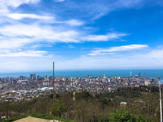 The view from the top from a height of a beautiful tourist city with buildings and houses, roofs of trees and plants, nature against a blue sky and mountains. European old architecture