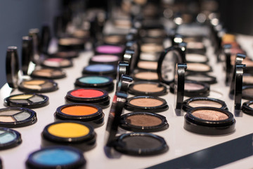 Different colors of eye shadow on the shop window in the cosmetic store. Test sample. Front view
