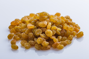 golden raisins on a white acrylic background