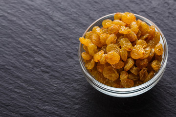golden raisins on a dark stone background