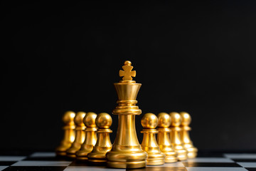 Gold king chess piece stand in front of pawn on black background (Concept of leadership, management)