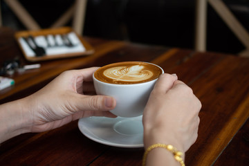 People are drinking a latte in a coffee shop.