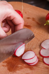 young woman in a gray apron cuts a radish