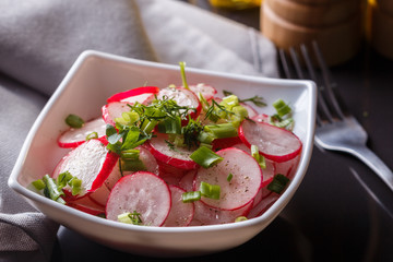 Radish salad in a white bowl on a dark background