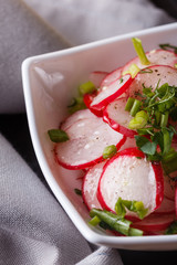 Radish salad in a white bowl on a dark background