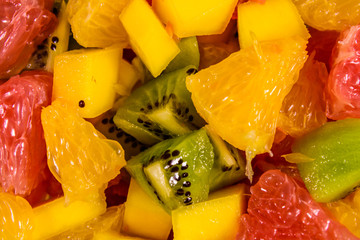 Background of the chopped exotic fruits. Mango, oranges, grapefruit and kiwi