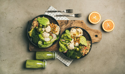 Healthy dinner, lunch setting. Flat-lay of vegan superbowls or Buddha bowls with hummus, vegetables, fresh salad, beans, couscous and avocado on wooden board and green smoothies, top view