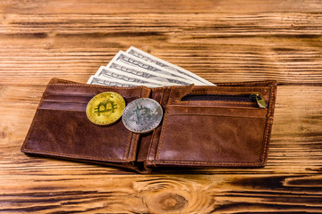 Brown leather wallet, bitcoins and one hundred dollar banknotes on the wooden background