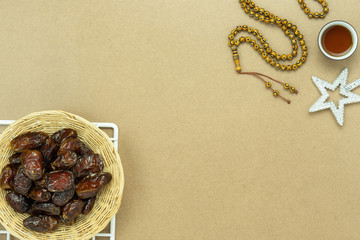 Table top view aerial image of decoration Ramadan Kareem holiday background.Flat lay date with rosary & lighting and cup of tea.Essential object on modern rustic brown wooden at office desk.copy space