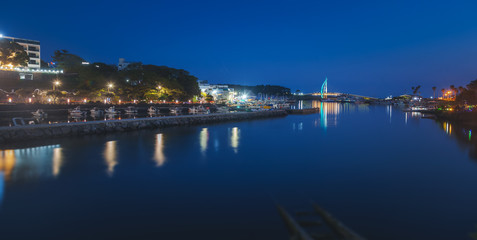 Obraz premium Bright night landscape, bridge in Seogwipo-si Jeju Island, South Korea. Night illumination, long exposure